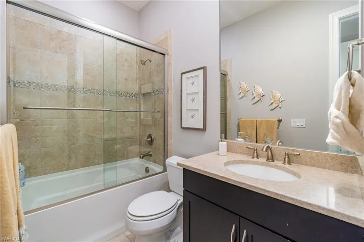 Full bathroom featuring toilet, combined bath / shower with glass door, and vanity