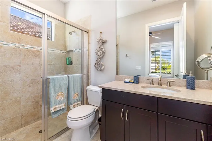 Bathroom featuring tile patterned flooring, a shower with door, vanity, and toilet