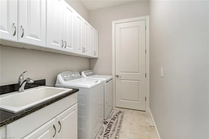 Laundry room featuring washer and clothes dryer, cabinets, and sink