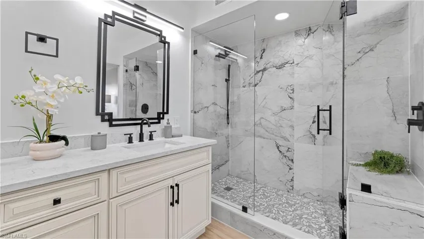 Full bath featuring a marble finish shower, vanity, and recessed lighting