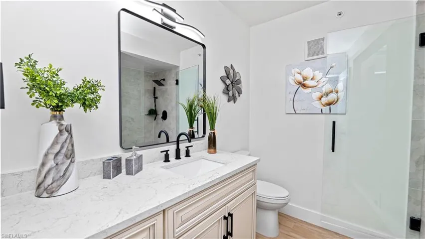 Full bath featuring vanity, a shower stall, and light wood-type flooring