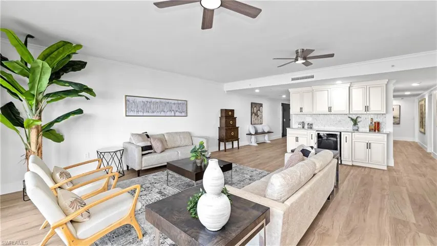 Living area featuring a ceiling fan, crown molding, light wood-style floors, beverage cooler, and recessed lighting