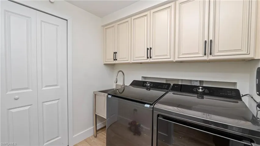 Laundry room with light wood-style flooring, washing machine and clothes dryer, and cabinet space