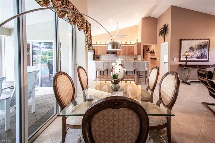 Dining space with light tile patterned flooring and high vaulted ceiling