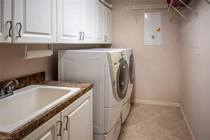 Laundry area featuring separate washer and dryer, light tile patterned flooring, and cabinet space