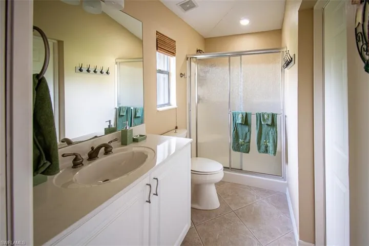 Full bathroom with a shower stall, vanity, and light tile patterned flooring