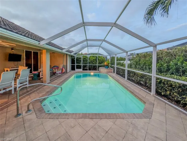 Swimming pool featuring a sunroom, glass enclosure, and a patio