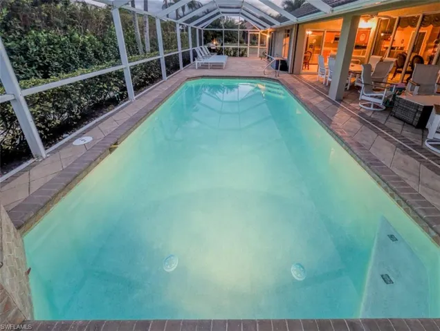 Outdoor pool with a sunroom, a patio, and glass enclosure