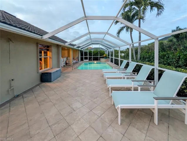 View of patio featuring a sunroom, an outdoor pool, and glass enclosure