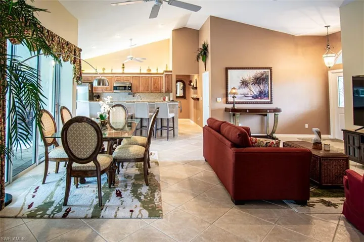Living room featuring high vaulted ceiling, light tile patterned floors, and ceiling fan