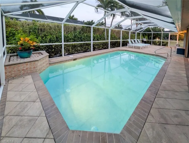 Outdoor pool with a patio, a sunroom, and glass enclosure