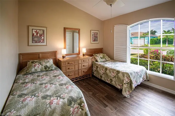 Bedroom with dark wood-type flooring, lofted ceiling, and a ceiling fan