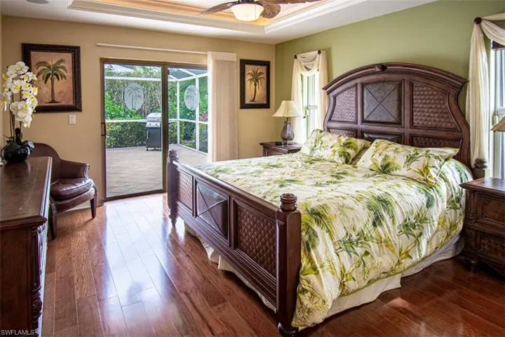 Bedroom featuring dark wood finished floors, a raised ceiling, and access to outside