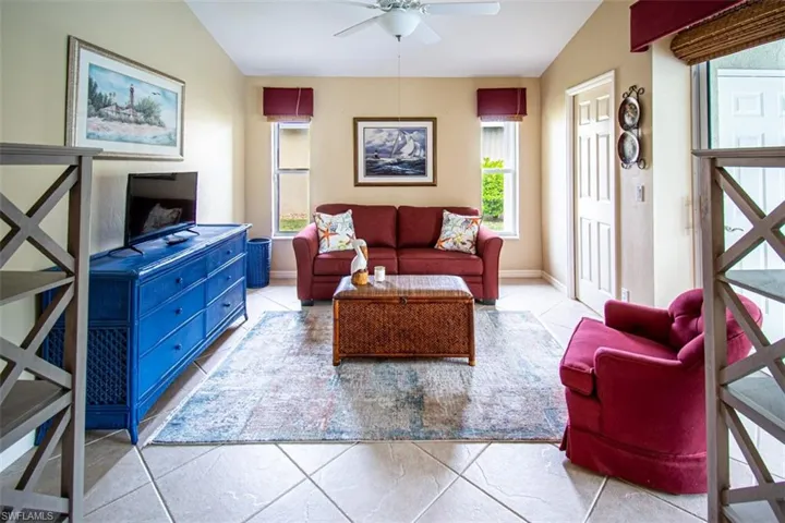 Living area with lofted ceiling, light tile patterned floors, and ceiling fan