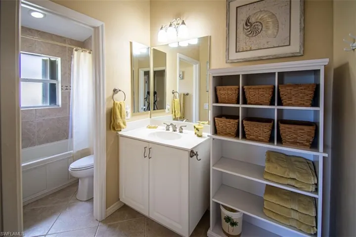 Bathroom featuring shower / bath combination with curtain, vanity, and light tile patterned floors