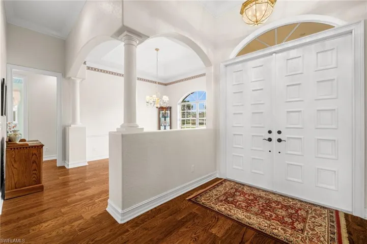 An impressive foyer welcomes guests with soaring ceilings, architectural archways, abundant natural light, and rich wood flooring that flows throughout the main living areas.