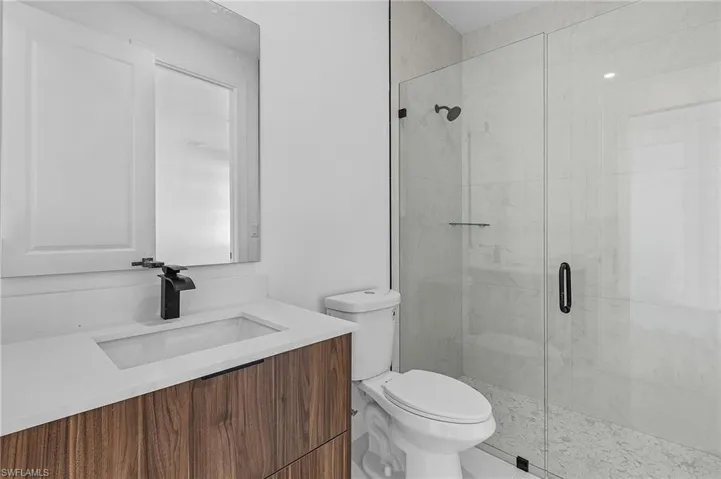 Bathroom with an enclosed shower, vanity, and toilet