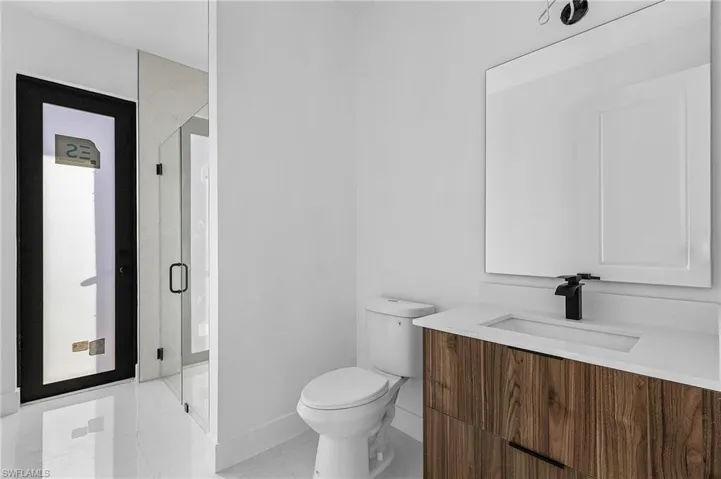 Bathroom featuring vanity, a shower with shower door, and toilet
