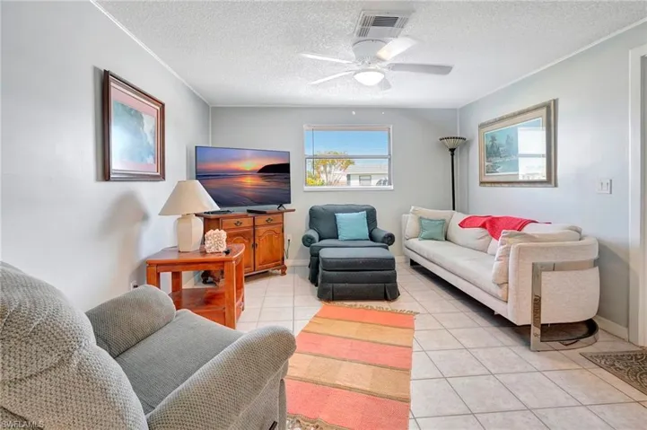 Tiled living room featuring ceiling fan and a textured ceiling
