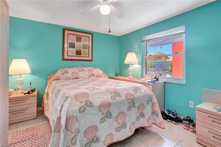 Tiled bedroom featuring ceiling fan and a textured ceiling
