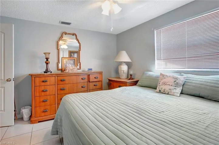 Tiled bedroom featuring a textured ceiling and ceiling fan