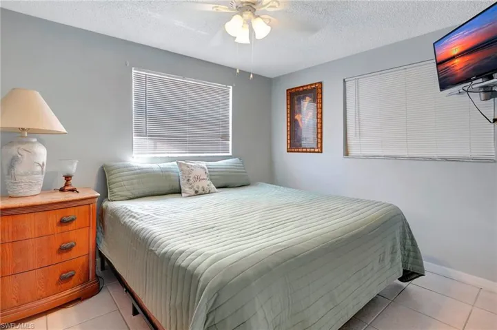 Tiled bedroom with a textured ceiling and ceiling fan