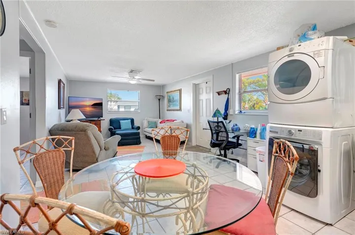 Dining room with a textured ceiling, ceiling fan, stacked washer / dryer, and light tile floors