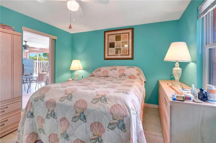 Bedroom featuring ceiling fan, light tile flooring, and access to exterior