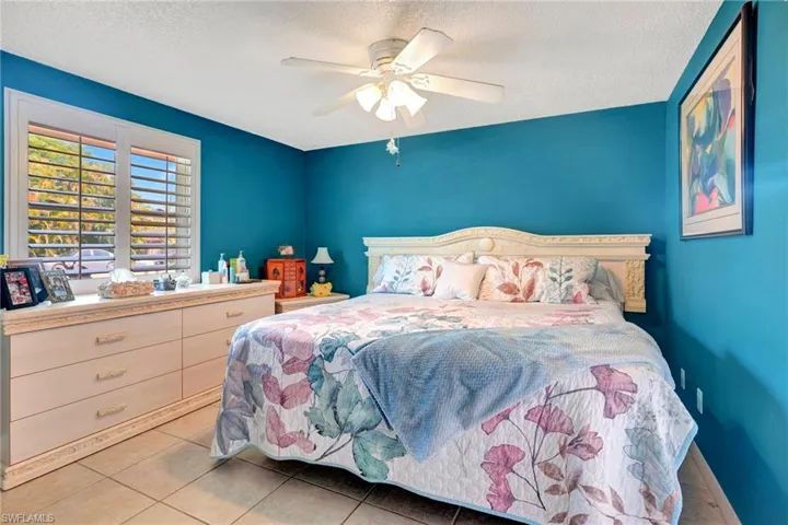 Bedroom with ceiling fan, a textured ceiling, and light tile floors