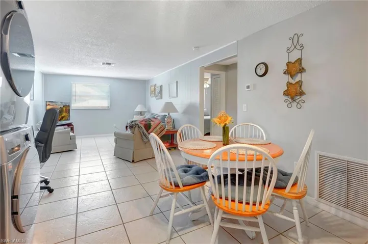 Tiled dining space featuring stacked washer and dryer and a textured ceiling