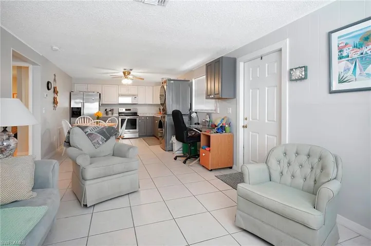 Tiled living room featuring ceiling fan and a textured ceiling