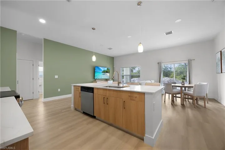 The kitchen features a center island with a sink, stainless steel dishwasher, and wooden cabinetry