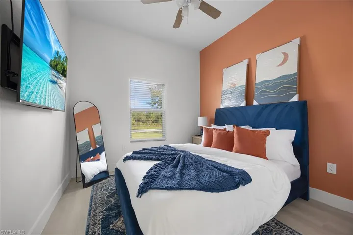 The room features light-toned flooring, a window with horizontal blinds, and a ceiling fan