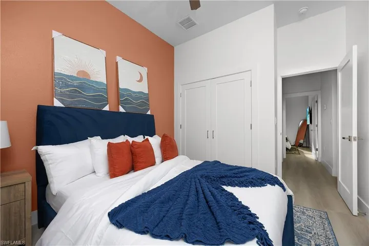 This room features an accent wall with a warm tone, white closet doors, and light-colored flooring