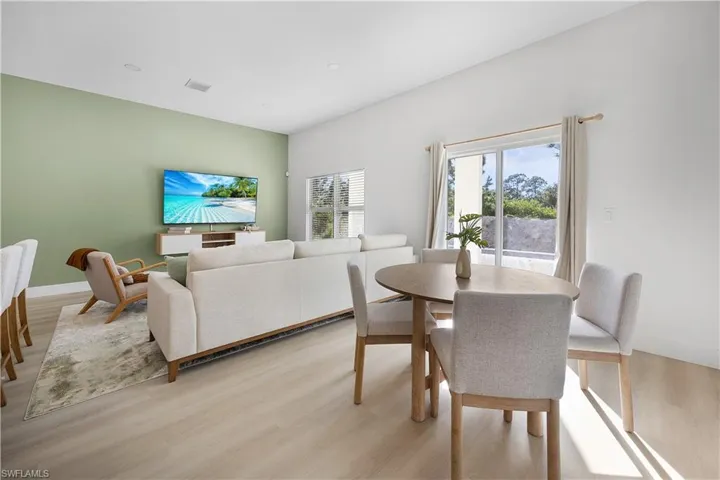 The property features an open living and dining area with light-colored flooring, a light green accent wall, and a sliding glass door leading to the exterior