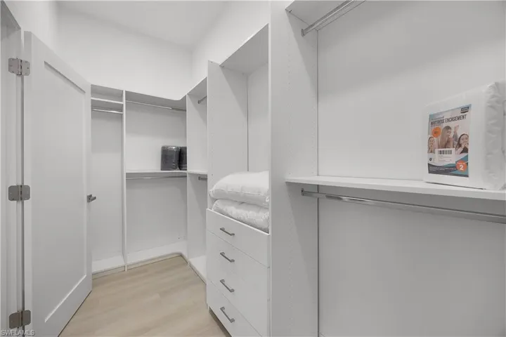 The property features a walk-in closet with light-toned flooring, white built-in shelving, and drawers