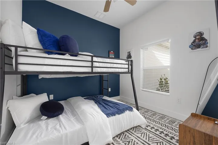 This room features a bunk bed with a dark metal frame, a window with blinds, and a distinctive patterned rug