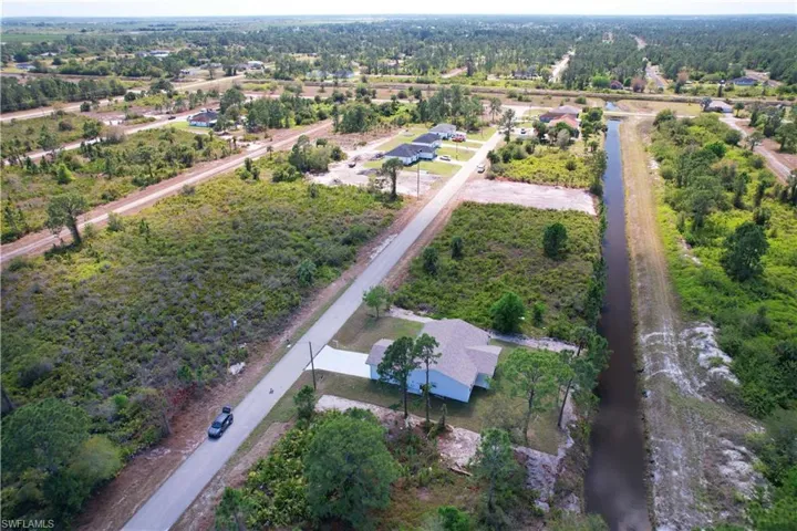 Aerial view of the property and its surrounding area, featuring a long, straight canal and abundant trees