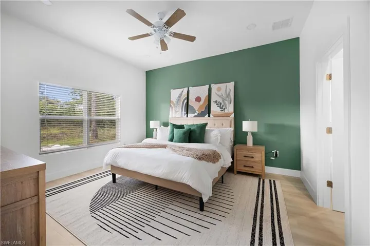 Bedroom featuring a contrasting accent wall, a window with blinds, and light-toned flooring