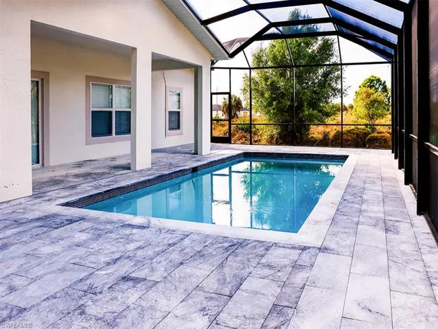 The property features a screened-in swimming pool area with a tiled deck and a pool with blue water