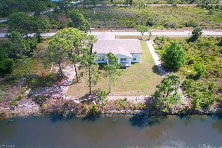 The property features a white exterior, a light-colored roof, and a well-maintained lawn