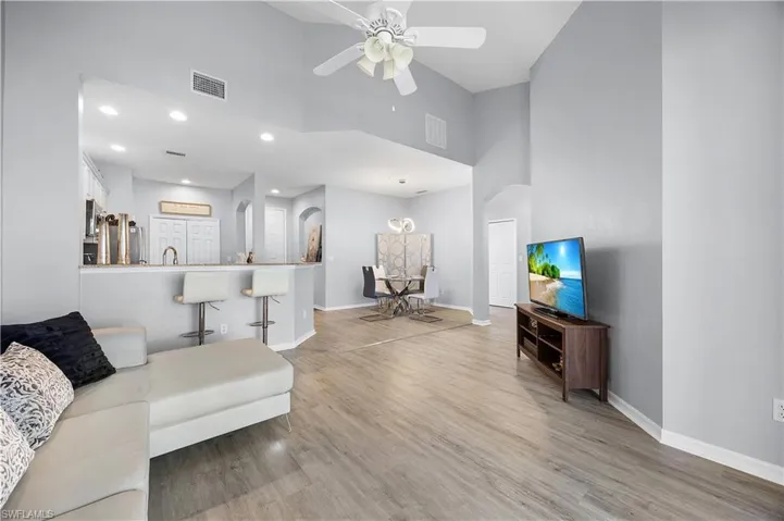 The open concept living area features light-colored flooring, recessed lighting, and a ceiling fan