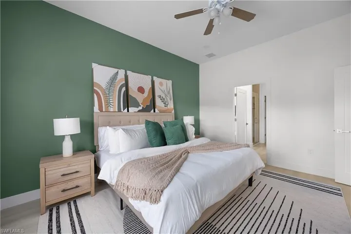 This bedroom features a striking accent wall, light-toned flooring, and a ceiling fan