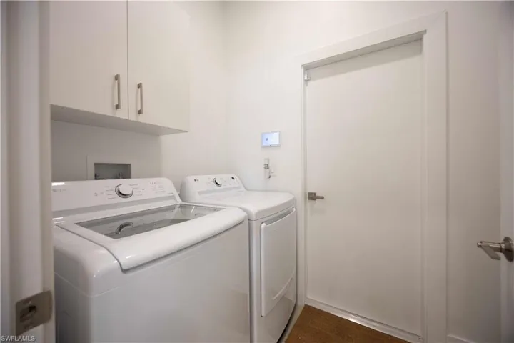 The laundry area features white cabinetry with silver hardware, a white top-loading washing machine, and a white dryer
