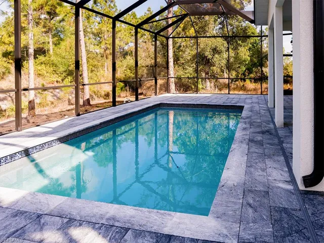 The property features a screened-in swimming pool, surrounded by a paved patio