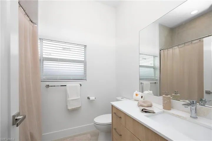 Contemporary bathroom with a light wood vanity, white countertop, and a large mirror