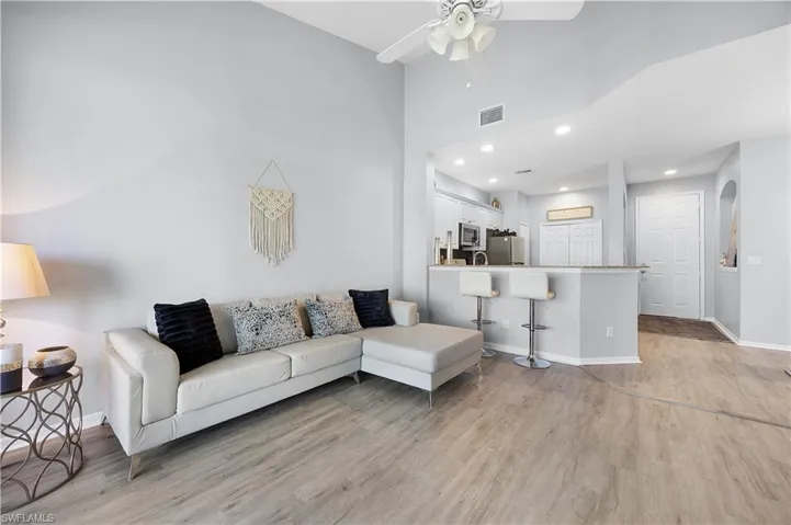 Living area with light-toned walls, vaulted ceilings, and light wood-style flooring