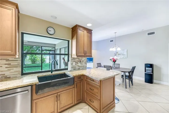 Kitchen with dishwasher, tasteful backsplash, light stone countertops, brown cabinetry, and recessed lighting