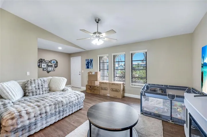 Living room with wood finished floors, lofted ceiling, and ceiling fan