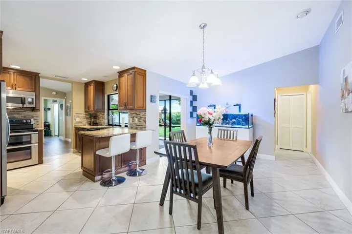 Dining space with vaulted ceiling, light tile patterned floors, a chandelier, and recessed lighting
